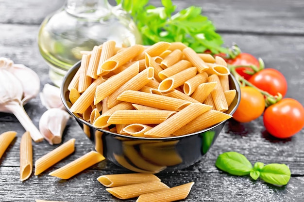 Penne whole grain in bowl with vegetables on board