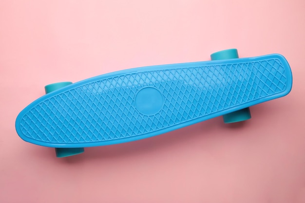 Penny skate board blue with blue wheels on pink background top view