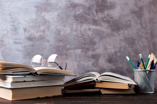 Pens, apple, pencils, books and glasses on the table