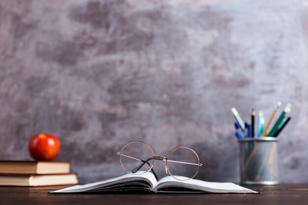 Pens, apple, pencils, books and glasses on the table