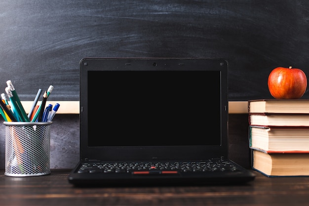 펜, 사과, 연필, 책, 노트북 및 칠판 배경에 테이블에 안경