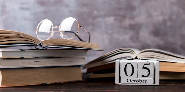 Pens, pencils, books and glasses on the table. Calendar october 5, copy space.