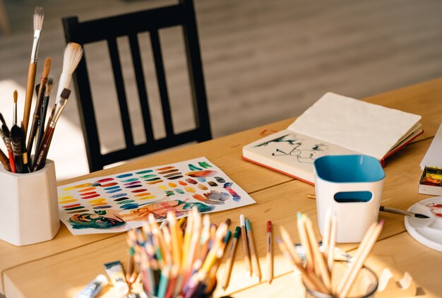 Penseel met buizen van olieverf en kleurpotloden. Kunst en ambachtelijke tools, inkt, houten tafel. Schilderen voor hedendaagse kunstenaars. Items voor de creativiteit van volwassenen. Aquarel tekenen. Sfeervolle moderne foto