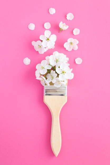 Penseel met witte bloemen op het roze oppervlak