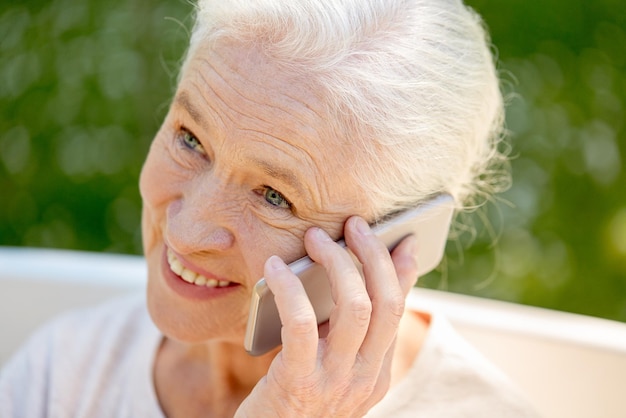 pensioen, communicatie en ouderenconcept - close-up van een gelukkige oudere vrouw die in de zomer op een smartphone belt