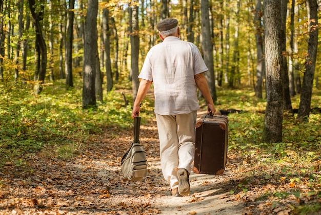 Pensioenreizen en hobby's Altijd een tas klaar voor gebruik Ouderen dragen reistas Oude man reizen met retro tas Leven als zwerver Vakantie en reizen Wanderlust Thuis is waar de tas landt
