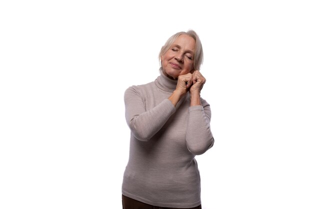 Pensioner woman with gray hair wearing a turtleneck on a white background with copy space