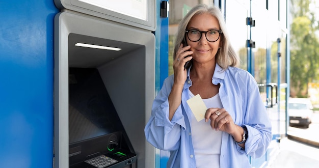 연금 수령자 여성이 길거리 ATM에서 현금을 인출합니다.