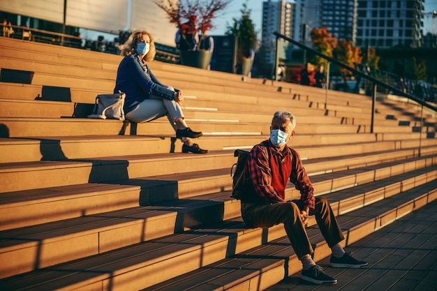 Pensioners sitting on stairs and wearing protective masks.