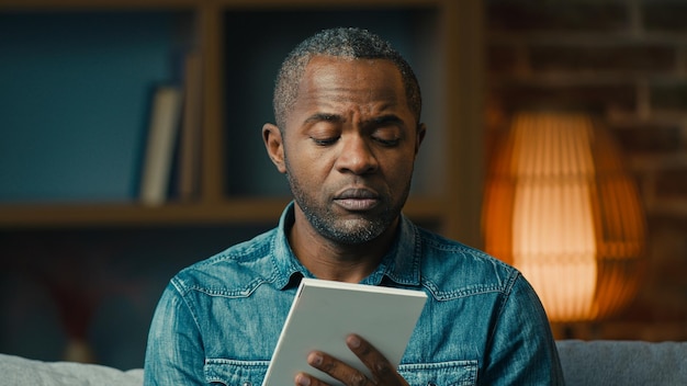 Pensive adult african American thoughtful businessman making notes in notebook