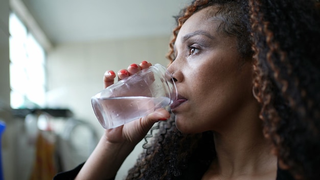 a pensive african woman drinking water thoughtful person drinks refreshment