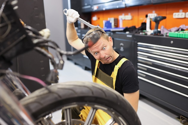 Pensive apprentice trainee locksmith thinks how to fix motorcycle motorcycle repair training