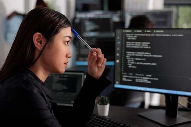 Pensive asian it programmer thinking at html script\
development, brainstorming ideas to create html code. it software\
developer working at database server in software office\
company