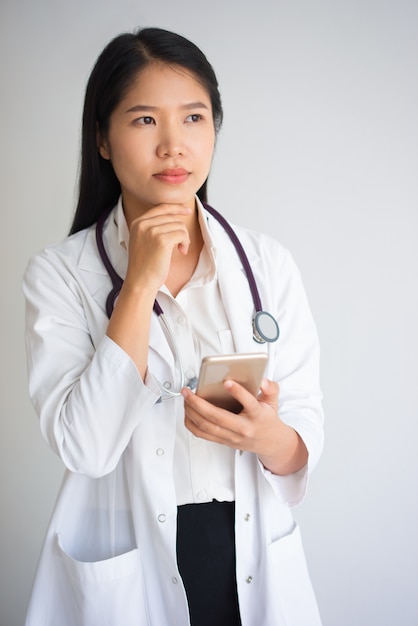 Pensive Asian Medical Student Using Phone