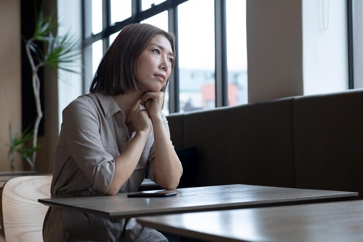 사무실 구내식당에서 창밖을 내다보는 잠겨있는 아시아 여성. covid 19 코로나바이러스 전염병 동안 비즈니스 사무실 직장에서 사회적 거리두기.