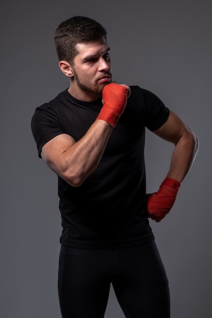 pensive athletic man with boxing wrist wraps on grey wall