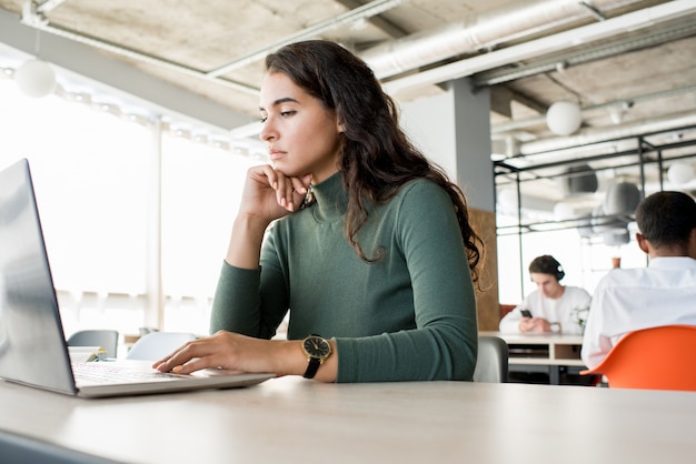 Bella donna pensierosa che per mezzo del computer portatile