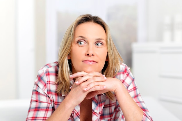 Pensive blond woman at home on sofa