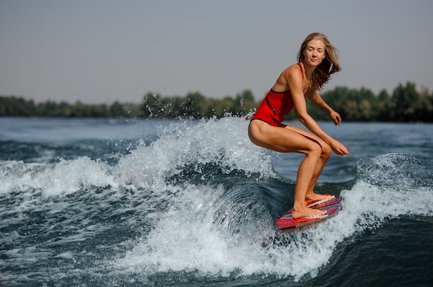빨간 wakeboard를 타고 잠겨있는 금발 소녀
