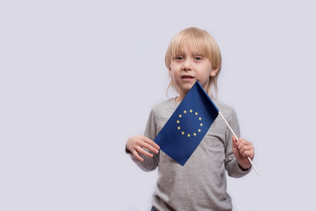 Pensive boy holding flag of European Union. Traveling with children in Europe.