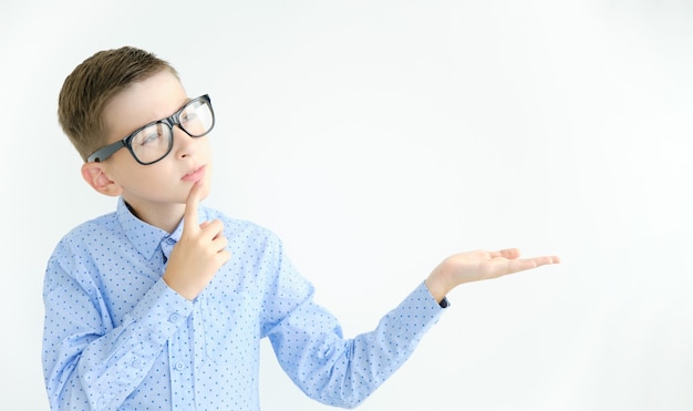 Photo a pensive boy points with his hand to an empty space for text.