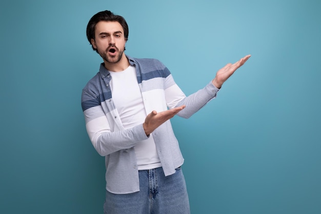 Pensive brunette guy in a model appearance dreams on a studio background