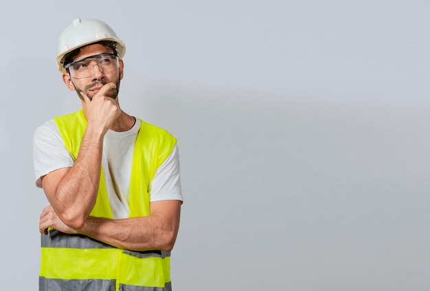 Pensive builder man with hand on chin Portrait of young builder thinking with hand on chin isolated A pensive engineer on white background Concept of a meditative engineer solated