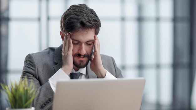 Pensive businessman sitting at the table with laptop