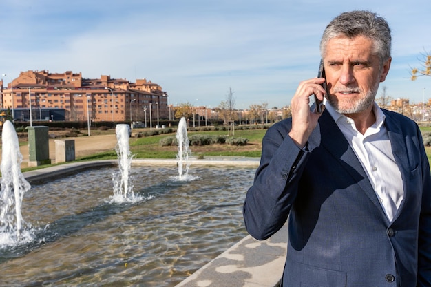 Pensive businessman talking on smartphone in city