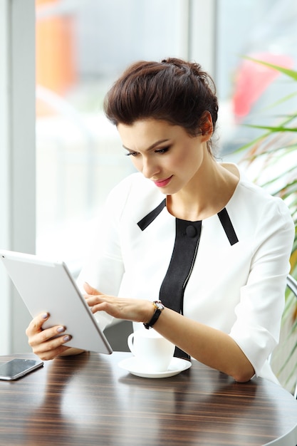 Pensive businesswoman reading an article on tablet computer in a cafe