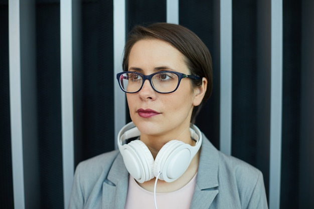 Pensive businesswoman with headphones on neck