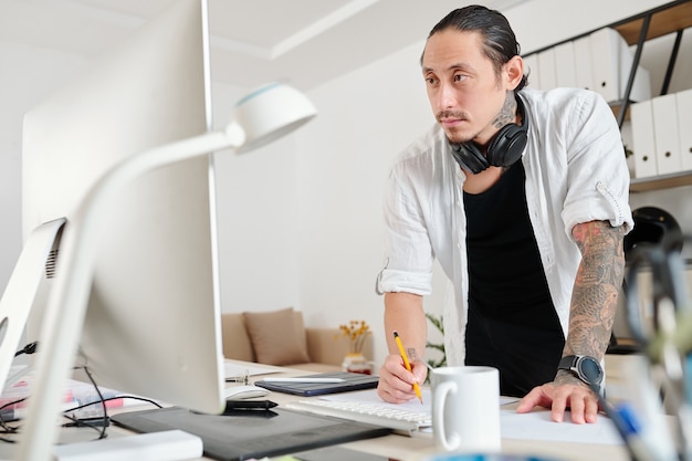 Pensive designer reading e-mail from client when drawing logotype for a big company