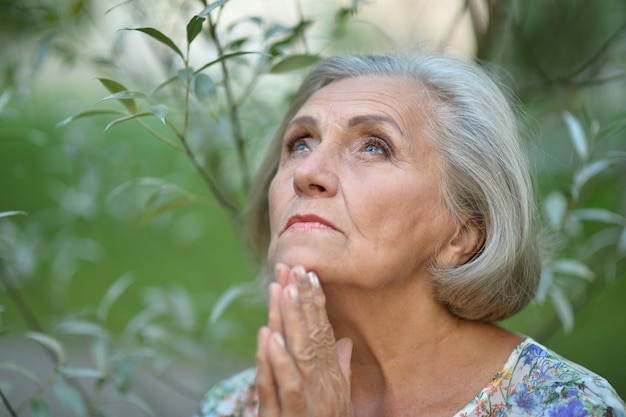 Pensive elderly woman in a summer park