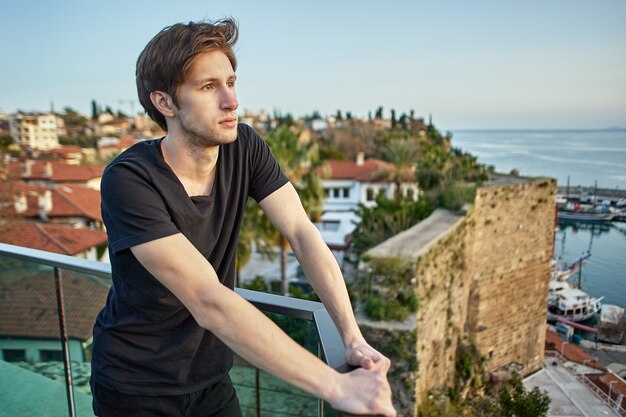 Pensive european man looks at old city in antalya from vantage point