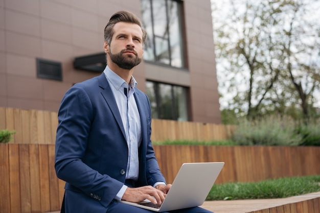 Libero professionista pensieroso che utilizza il computer portatile digitando il progetto di pianificazione che lavora da casa