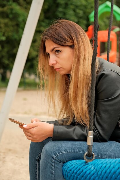 彼女の手で電話を持っている物思いにふける女の子電話でブルネット