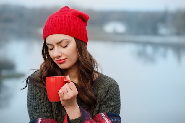 物思いにふける女の子が屋外でコーヒーを飲む