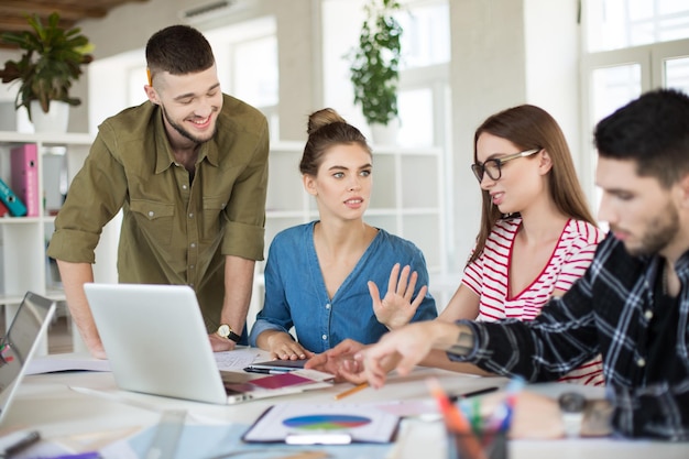 Pensive girl in shirt thoughtfully looking aside while spending time at work Young creative people discussing new project together in modern office