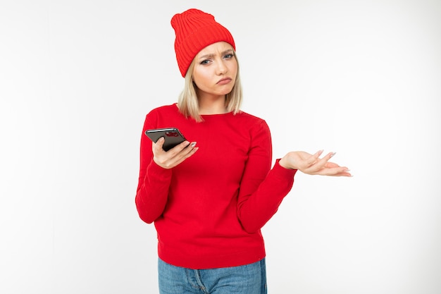 Pensive girl with a smartphone in her hands argues on a white background with copy space