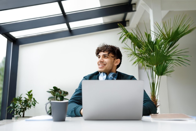 Pensive guy looking away while working on laptop dreamy male freelancer thinking on ideas sitting in