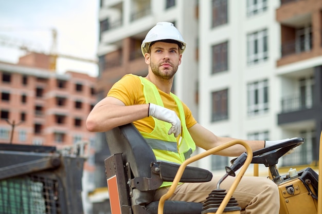 pensive man driving excavator at construction site