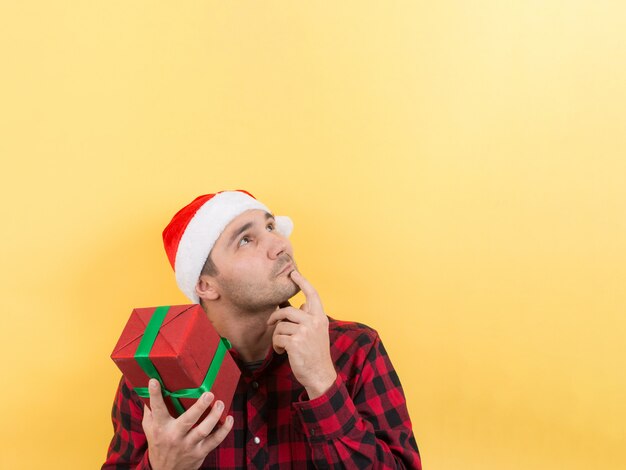 Pensive man in a red hat holds a gift with interest on his face