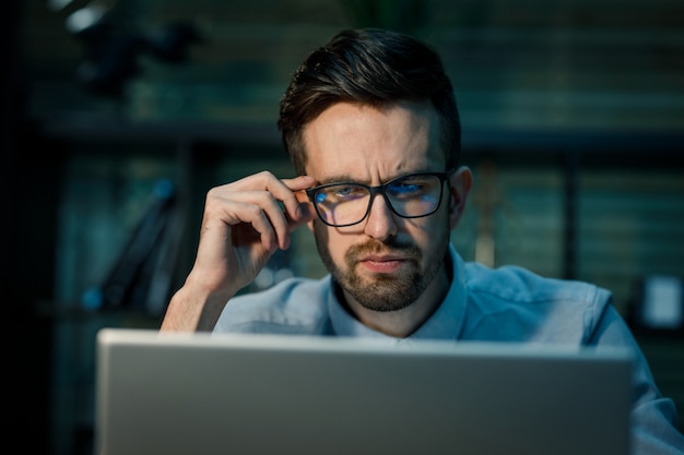 Foto uomo pensieroso che lavora al computer portatile