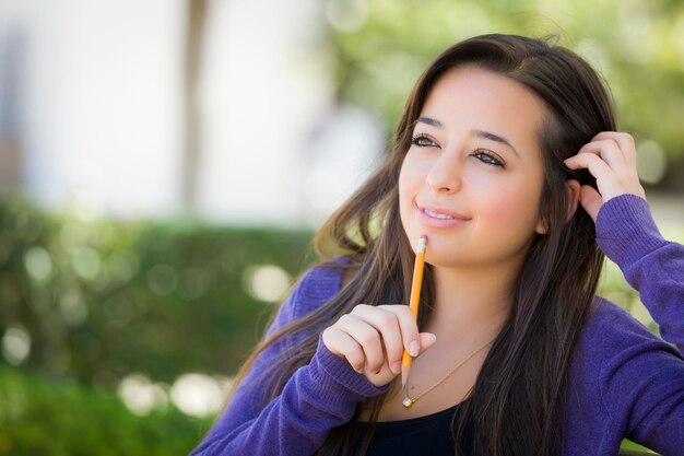 Photo pensive mixed race female student with pencil on campus