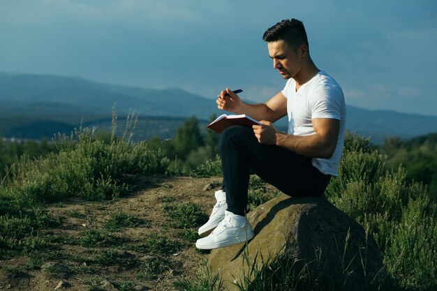 Pensive muscular man with book outdoor