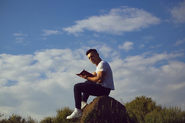 Pensive muscular man with book outdoor