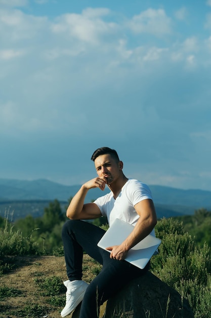 Pensive muscular man with laptop outdoor