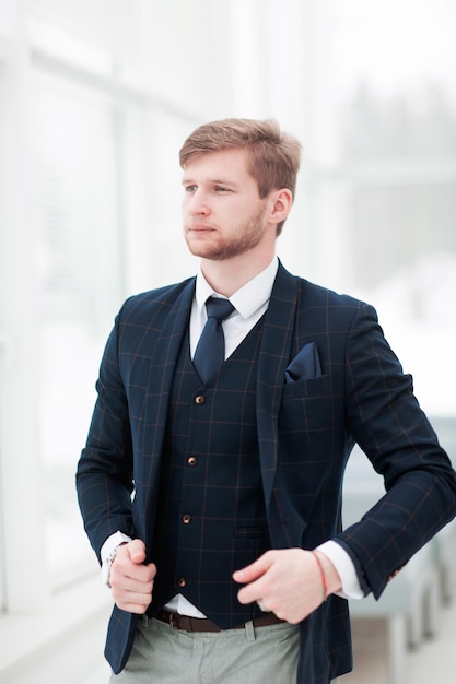 Pensive newcomer businessman in a business suit stands near a wi