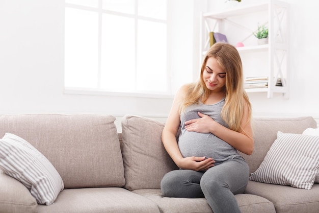 Pensive pregnant woman dreaming about child. Young happy expectant thinking about her baby and enjoying her future life. Motherhood, pregnancy, happiness concept