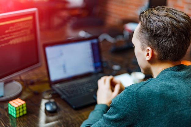 Pensive programmer working on a desktop pc programming code technologies on blurred computer background Website design at office software development company